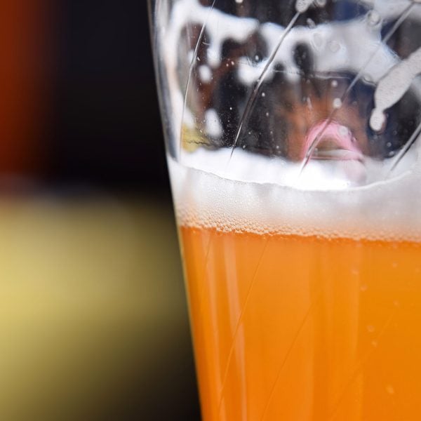 Close up one full glass of unfiltered wheat beer on table, with copy space, low angle side view