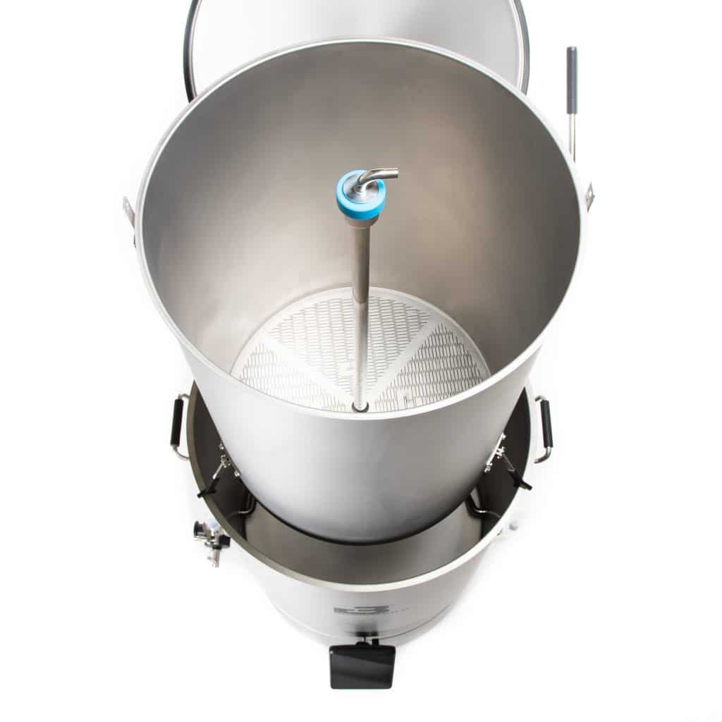 Top-down view of an open stainless steel drum with a blue-valved central tube and vertical pipe inside.