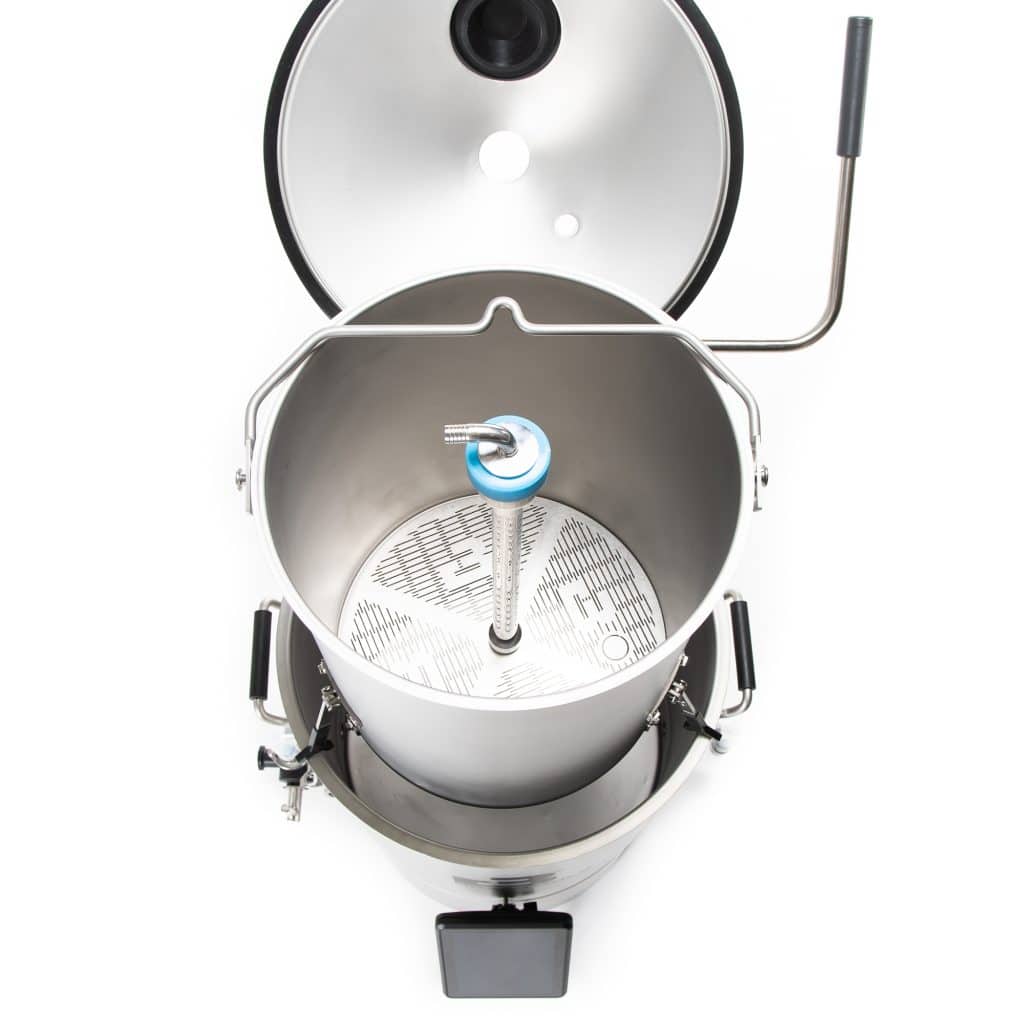 Top-down view of an open stainless-steel pressure cooker showing the inner pot with a perforated base and the safety valve assembly visible on the lid side.