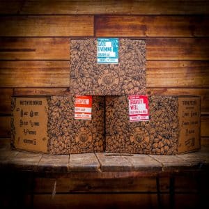 Boxed beer with a blue and white label reading 'Late Evening Golden Ale' stacked on wooden shelves, decorative brown patterns surrounding the box.