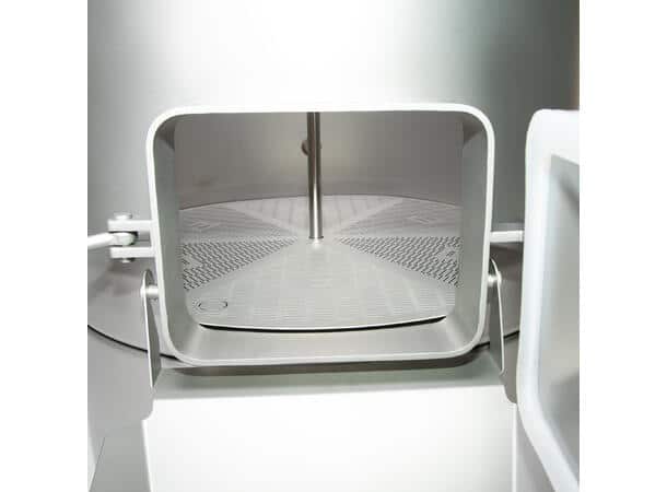 Open door of a laboratory instrument showing a circular perforated sample stage with a central rod