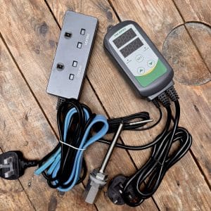 Inkbird temperature controller with probe and tangled cables on a wooden work surface, adjacent to a power block labeled HEATING and COOLING.