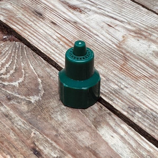 Close-up of a green spray bottle nozzle on a weathered wooden surface.