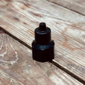 Close-up of a black spray bottle standing on a weathered wooden surface with visible grain.