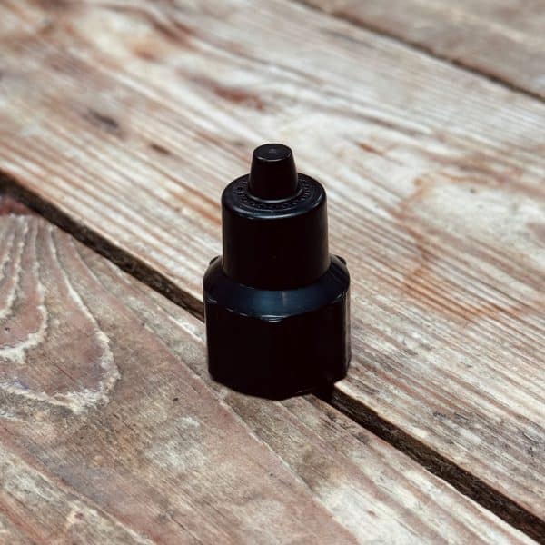 Close-up of a black spray bottle standing on a weathered wooden surface with visible grain.
