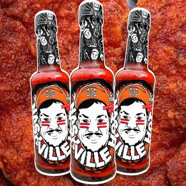 Three hot sauce bottles with red labels and black patterned caps, arranged in a row against a red textured background, bold caricature faces on labels.