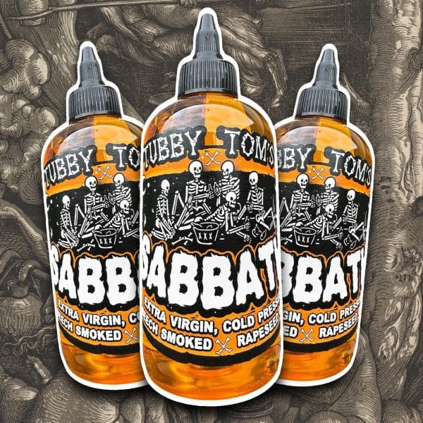 Three amber dropper bottles with a skeleton-themed orange-and-black label, text reads 'Extra Virgin, Cold Pressed Rapeseed Oil' against a dark patterned background.