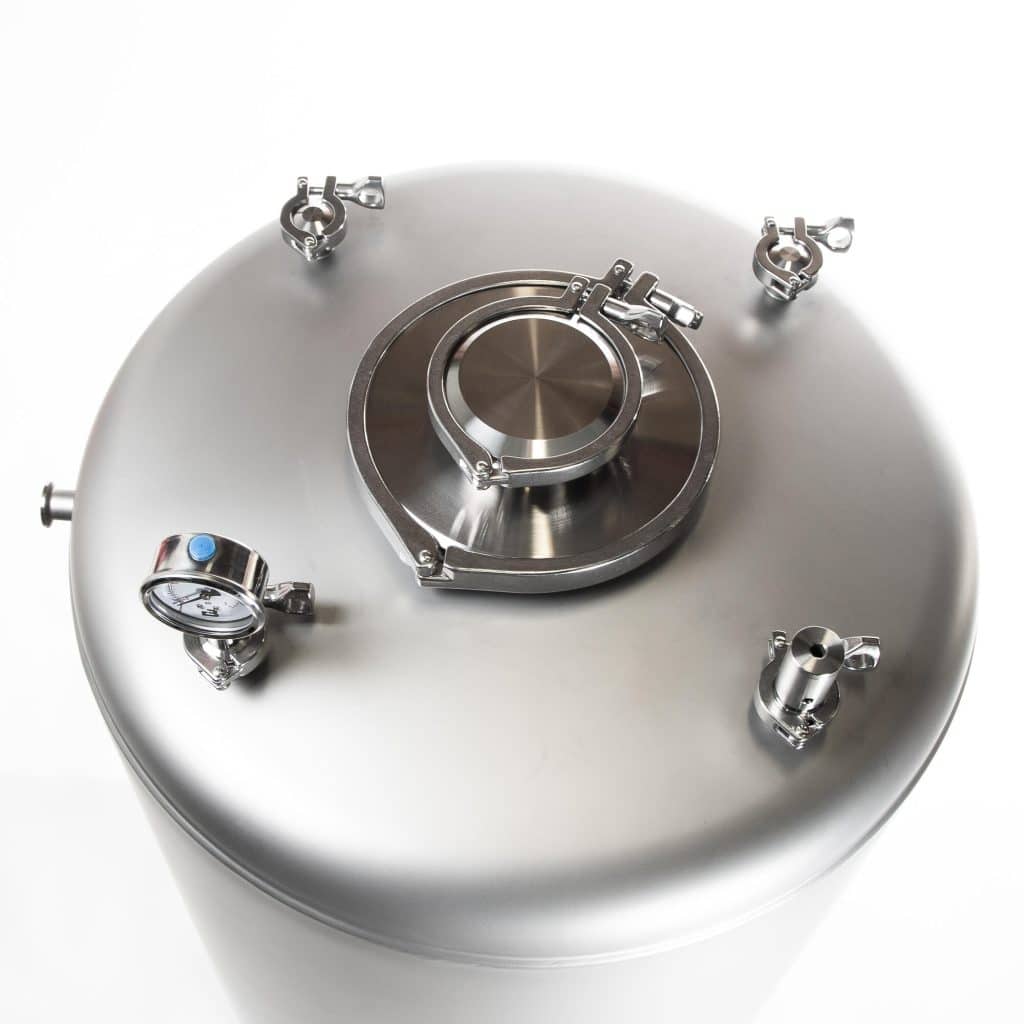 Close-up of a stainless steel pressure vessel lid with clamps and a circular flange in the center.